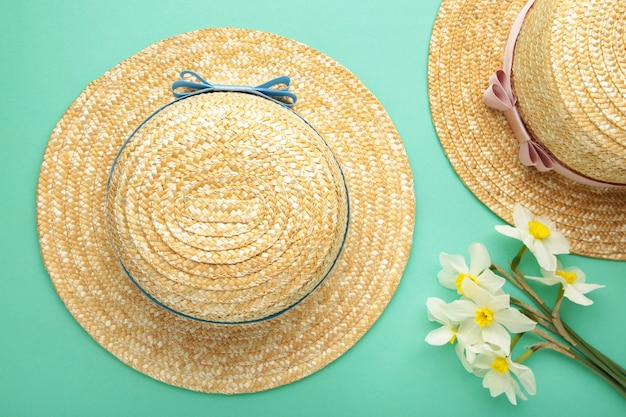 Chapeaux de paille avec des fleurs de printemps sur la surface de la menthe