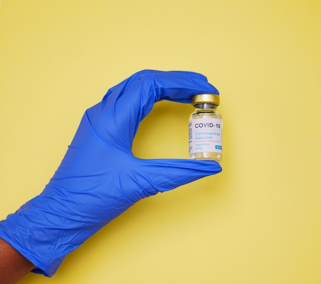 Chaque vaccin est manipulé avec soin Photo d'une personne non reconnaissable tenant des tubes de vaccin sur fond jaune