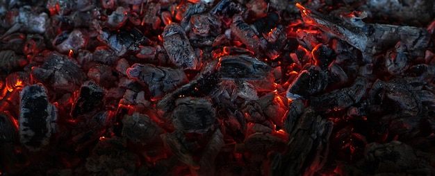 charbons ardents dans le noir charbon fumant étincelles rouge vif de fond de feu