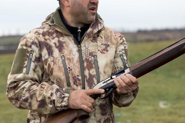 Charge un fusil de chasse à âme lisse chassant un faisan avec des chiens Un chasseur en tenue de camouflage se tient debout avec une arme