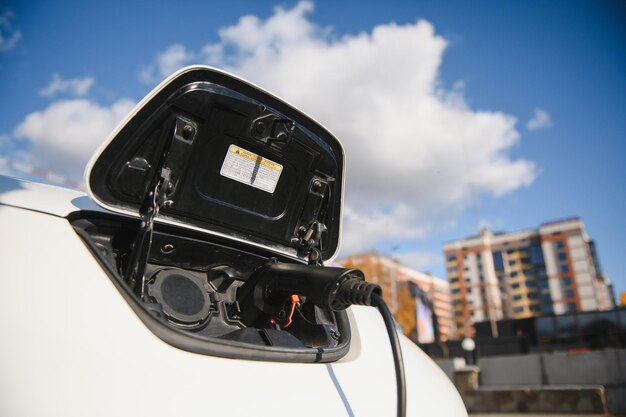 Chargement d'une batterie de voiture électrique moderne dans la rue qui est l'avenir de l'automobile, gros plan sur l'alimentation électrique branchée sur une voiture électrique en cours de charge pour l'hybride . Nouvelle ère du carburant pour véhicules.