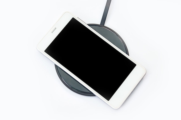 Chargement de smartphone sur un chargeur sans fil sur blanc