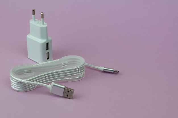 Chargement USB et câble pour appareils mobiles sur fond rose.