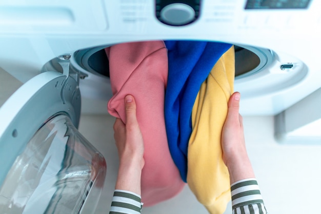 Chargement des vêtements et du linge de couleur dans la machine à laver. Faire la lessive à la maison. Vue de dessus