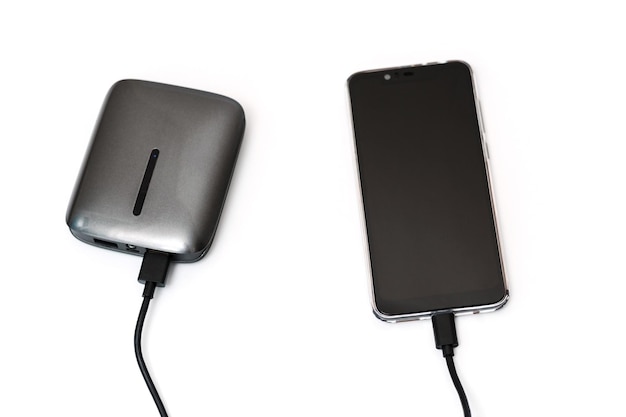 Charger votre smartphone à partir d'un chargeur portable libre La banque d'alimentation et le smartphone sont connectés par un câble et se trouvent sur fond blanc