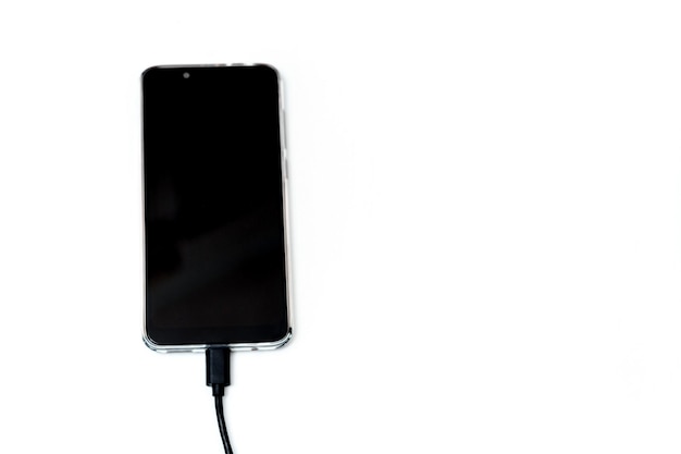 Charger votre smartphone à partir d'un chargeur portable libre Le smartphone est connecté par un câble et se trouve sur fond blanc