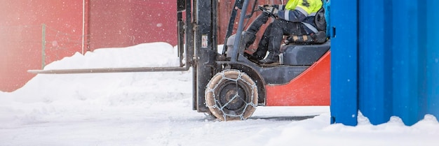 Chargeur de fret en hiver sur la neige le chargeur roule sur la neige avec des chaînes sur les roues pour réduire le glissement