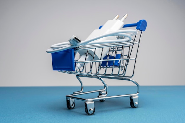 Un chargeur de téléphone dans un chariot de supermarché sur fond bleu