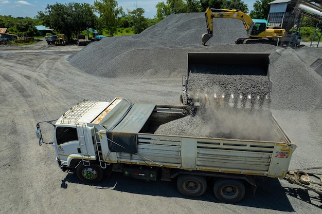 Les chargeurs de sable pelletent des pierres dans des camions à benne basculante