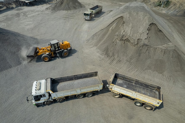 Photo les chargeurs de sable pelletent des pierres dans des camions à benne basculante