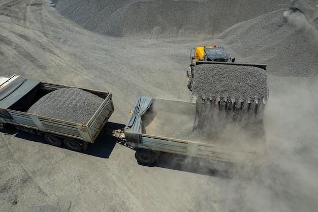 Les chargeurs de sable pelletent des pierres dans des camions à benne basculante