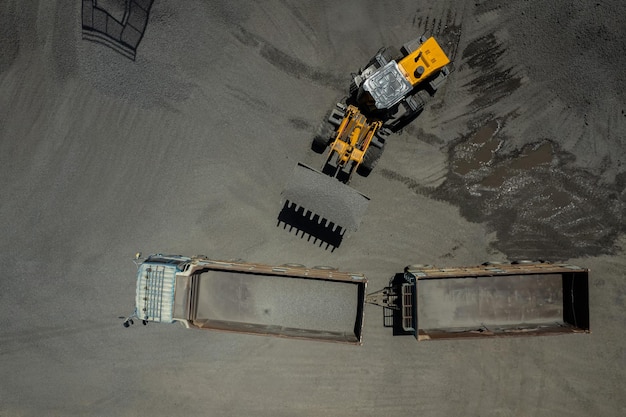 Les chargeurs de sable pelletent des pierres dans des camions à benne basculante