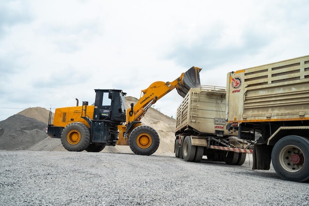 Les chargeurs de sable pelletent des pierres dans des camions à benne basculante