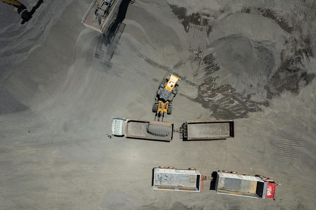 Les chargeurs de sable pelletent des pierres dans des camions à benne basculante