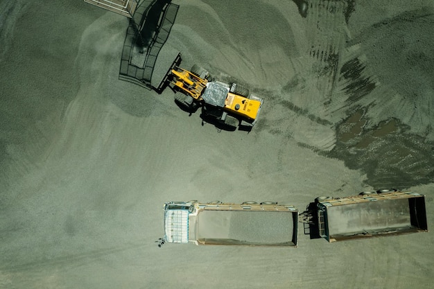 Les chargeurs de sable pelletent des pierres dans des camions à benne basculante