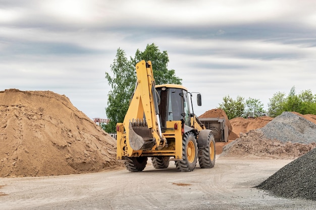 Chargeuse sur pneus ou bulldozer puissante sur le chantier La chargeuse transporte le sable dans un godet de stockage Puissant équipement moderne pour les travaux de terrassement et la manutention de vrac