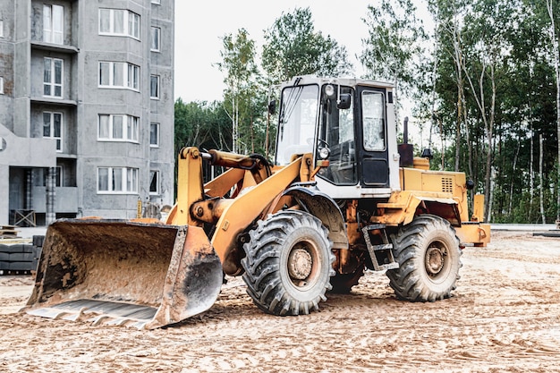 Chargeuse sur pneus lourde avec un godet sur un chantier de construction. Equipements pour les travaux de terrassement, le transport et le chargement de matériaux en vrac - terre, sable, pierre concassée.