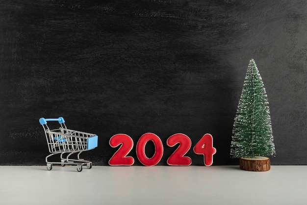 Photo chariot de chariot d'arbre de noël et numéros 2024 sur un fond clair achats pour la nouvelle année espace de copie