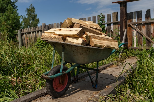 Un chariot de jardin avec du bois haché se dresse sur un pont en bois.