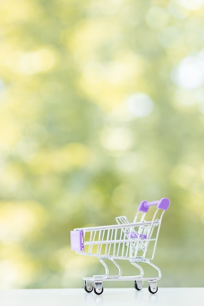 Chariot de magasinage de couleur minimal sur fond d'été vert