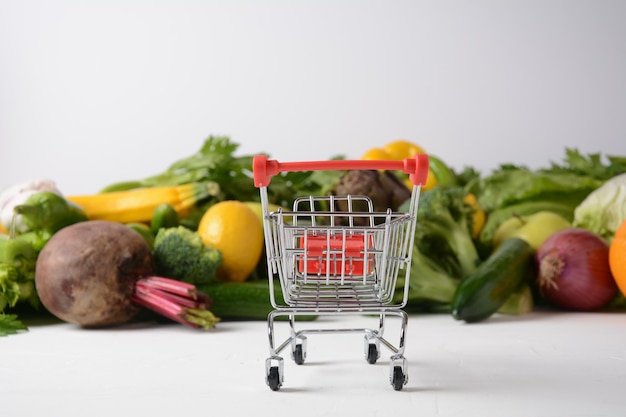 Chariot de magasinage et différents fruits et légumes frais pour la mise en page Assortiment de fruits et légumes frais Fond de nourriture saine Shopping alimentaire au supermarché