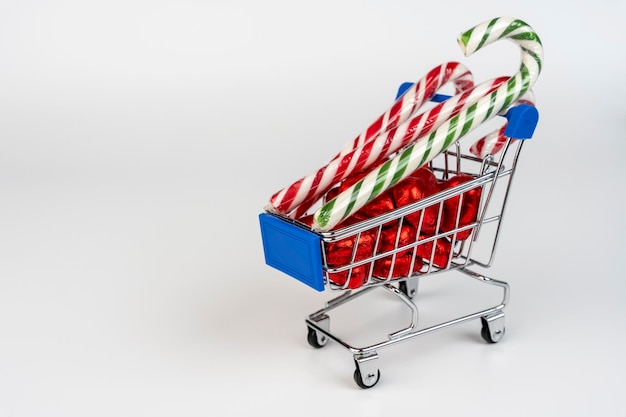 Un chariot de supermarché chargé de bonbons et de cannes de Noël au caramel