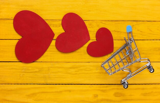 Chariot de supermarché avec des coeurs rouges sur un bois jaune