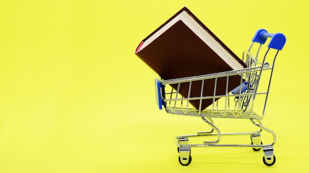 Photo chariot de supermarché en métal avec livre épais et espace de copie