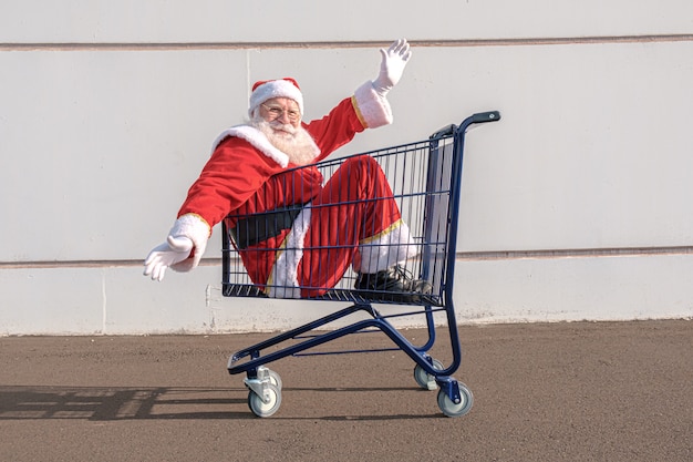 Chariot de supermarché avec le père Noël à l'intérieur. Shopping pour le concept de Noël.