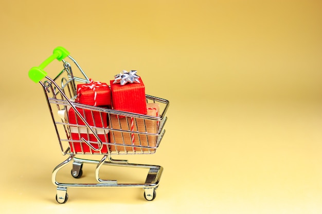 Chariot de supermarché plein de cadeaux sur un jaune