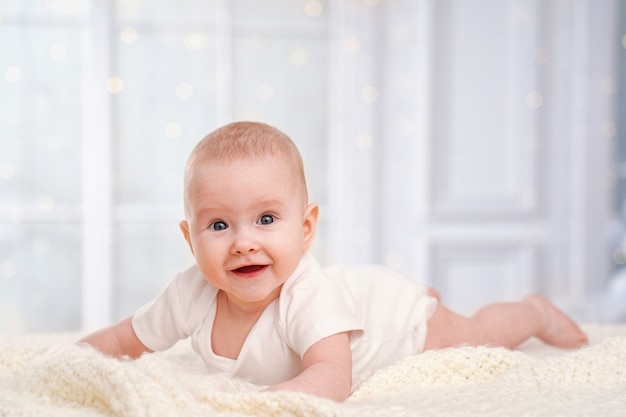 Charmant bébé mignon est allongé sur une couverture blanche