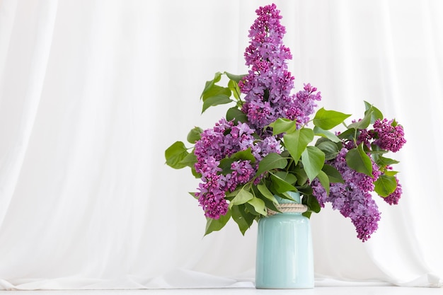 Charmant bouquet de lilas en fleurs dans un vase sur gris