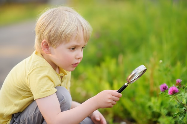 Charmant enfant explorant la nature avec une loupe