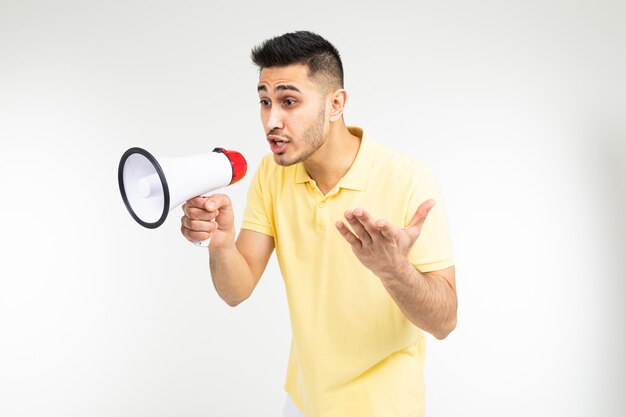 Charmant homme avec un mégaphone dans ses mains crie la nouvelle des remises pour les achats sur fond blanc