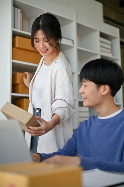 Un charmant jeune couple asiatique travaille dans son bureau pour vérifier les commandes en ligne