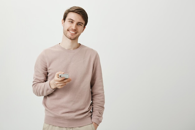 Charmant jeune homme mal rasé agréable debout avec un joli sourire