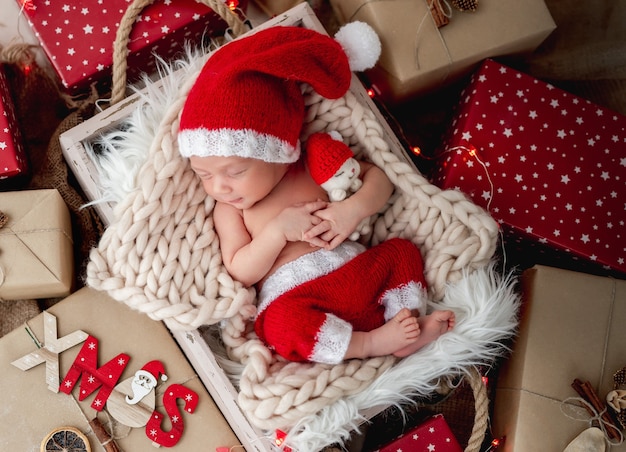 Charmant nouveau-né dormant entre les cadeaux de Noël