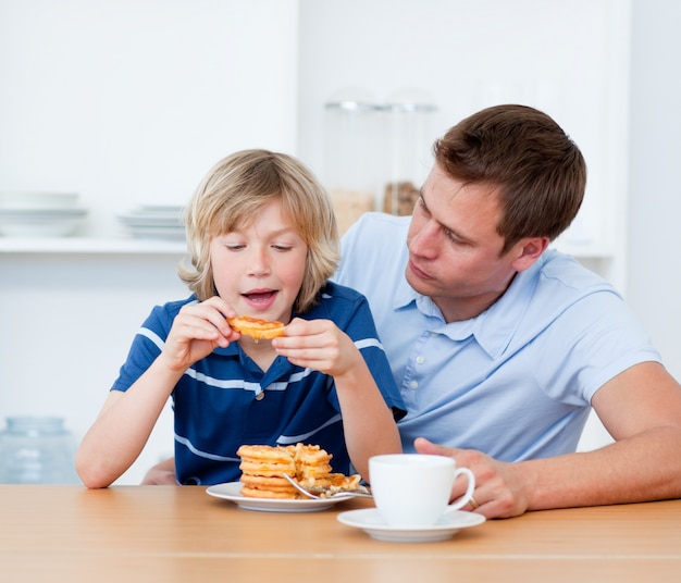 Charmant père et son fils mangeant des gaufres