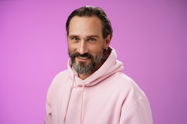 Charmant Séduisant Beau Barbu élégant Modèle Masculin Adulte Boucle D'oreille Rose à Capuche Souriant Ravi Express Confiance Positivité Se Sentir Chanceux Amusé, Debout Fond Violet Parler Avec Désinvolture.