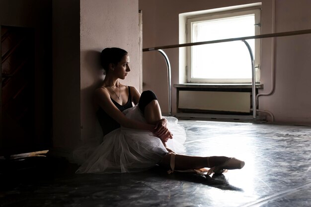 une charmante ballerine dans la classe de danse se réchauffe et répète une performance complètement immer