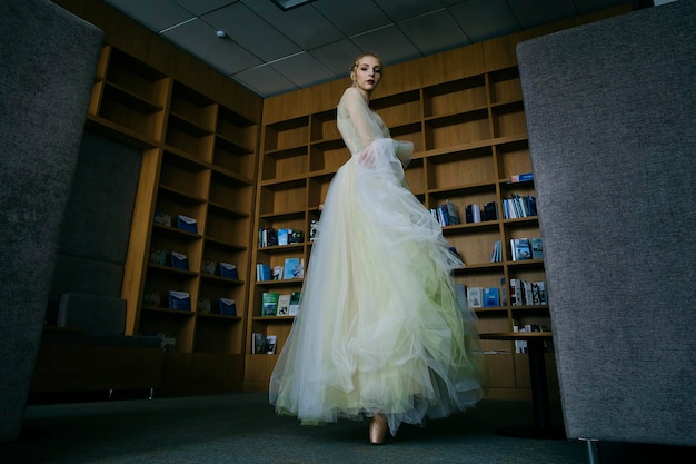 La charmante ballerine est allée à la bibliothèque pour choisir un nouveau livre pendant une pause montrant votre étirement et votre flexibilité