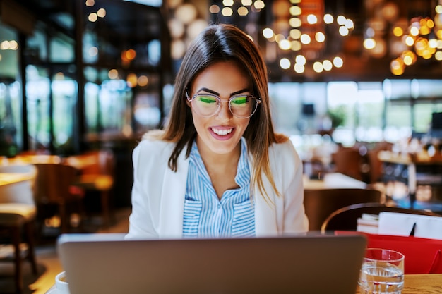 Charmante brune à la mode caucasienne assise dans un café après le shopping