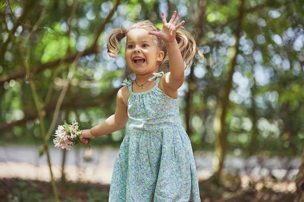 Charmante enfant en robe de soleil avec un bouquet de fleurs dans le jardin