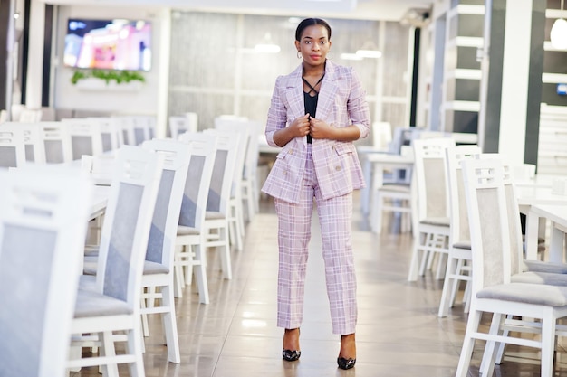 Charmante femme afro-américaine en veste posant au restaurant