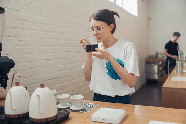 Charmante femme barista sentant le café à la cafétéria