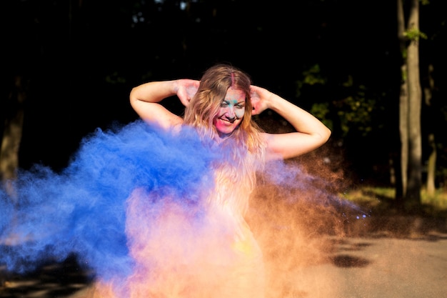 Charmante femme blonde s'amusant avec de la peinture Holi sèche qui explose