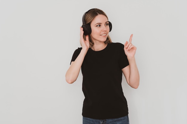 Charmante femme européenne en tenue décontractée, portant des écouteurs, écoutant de la musique