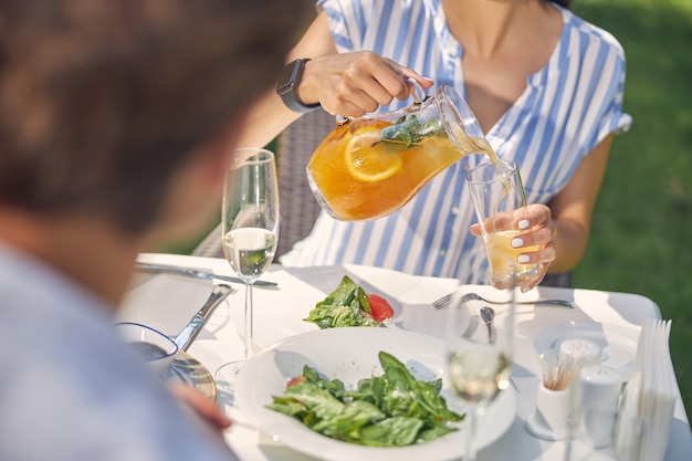 Charmante femme et homme se reposant à l'heure du déjeuner tout en mangeant un repas savoureux et en buvant de l'eau froide