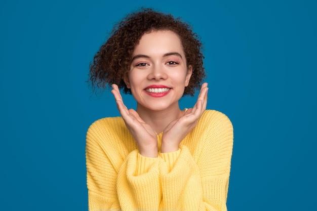 Charmante femme avec les mains près du visage en studio