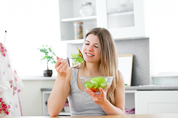 Charmante femme mangeant une salade dans la cuisine